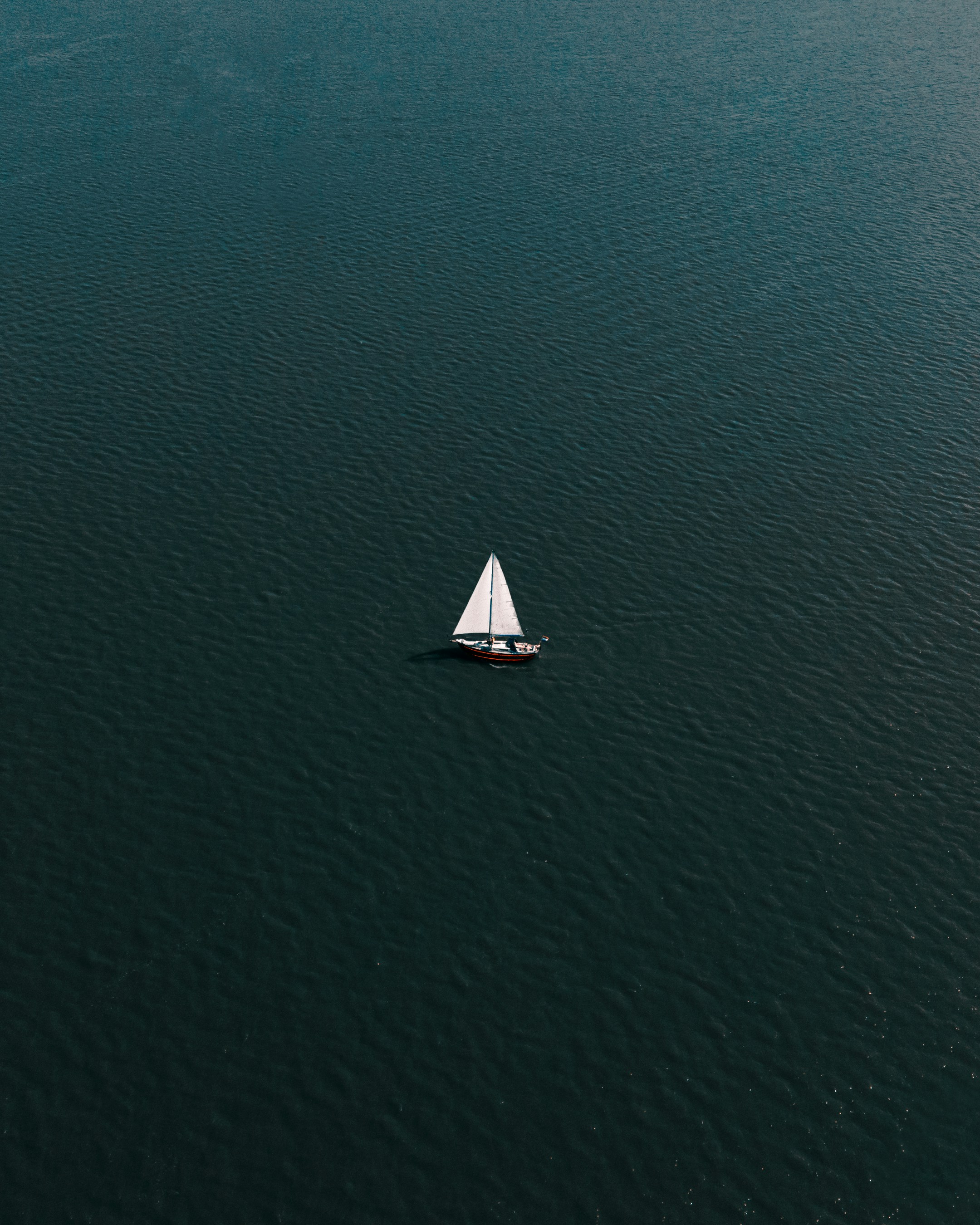 Aerial view of sailboat on teal ocean water